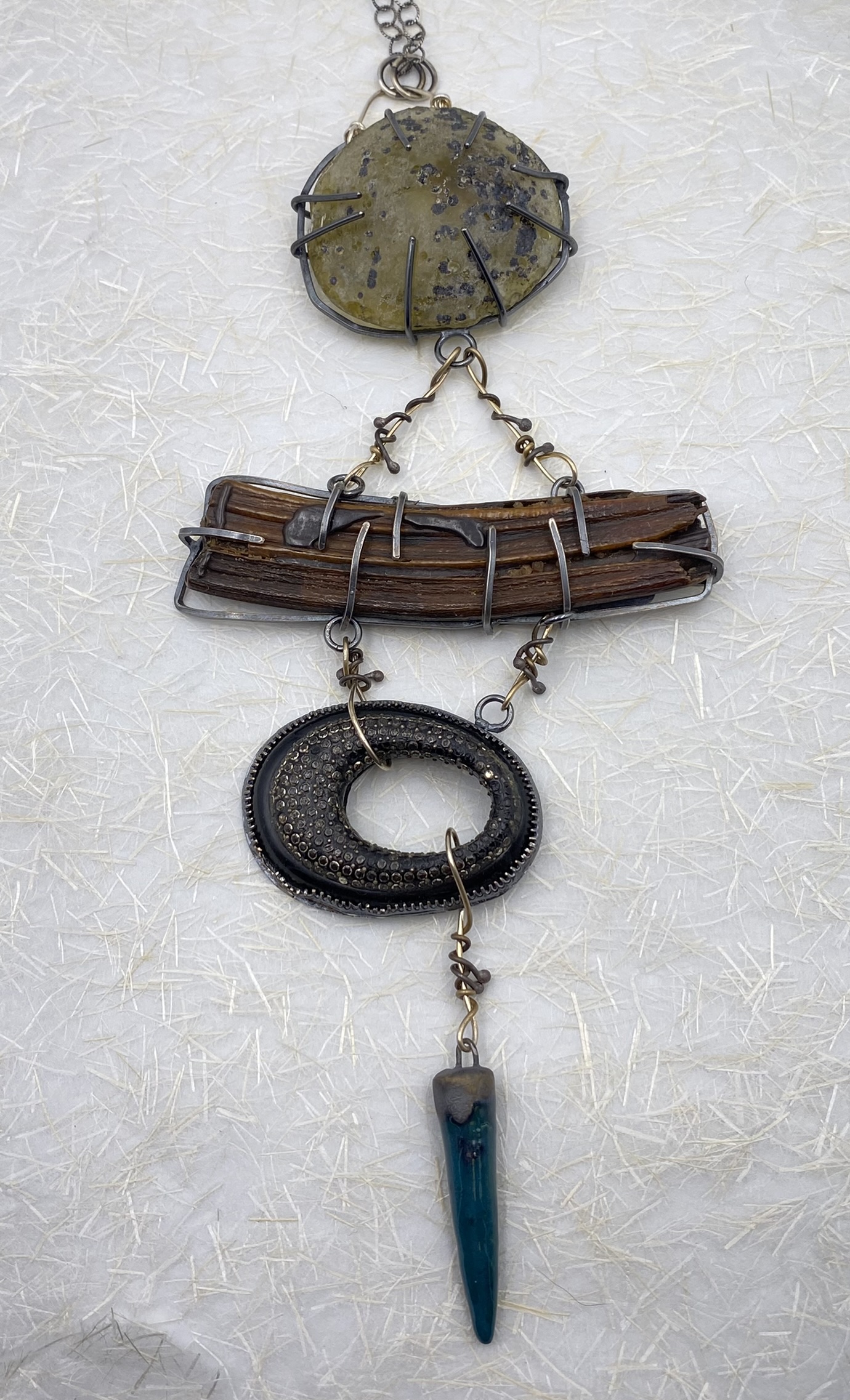 Round Roman glass above fossil Equus tooth a vintage black brooch with shiny bits, and a teal ceramic cone all caged in Sterling silver