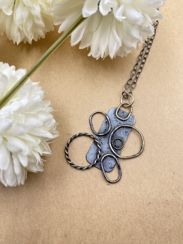 Sterling silver necklace. Rectangle silver piece with wire "petals" of different sizes and textures sticking out.