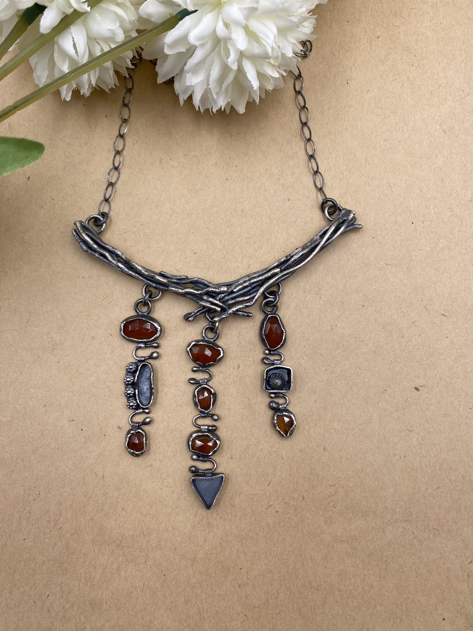 Sterling silver branches below which are three columns of sterling silver shapes interspersed between carnelian gems