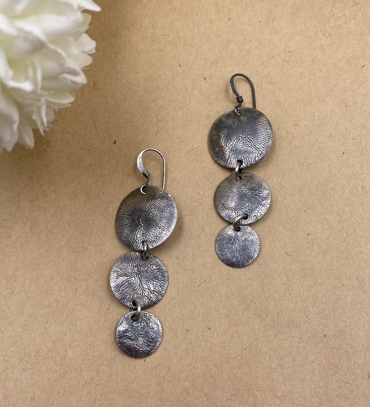 Three textured Sterling silver circles of descending size dangling from French hooks.