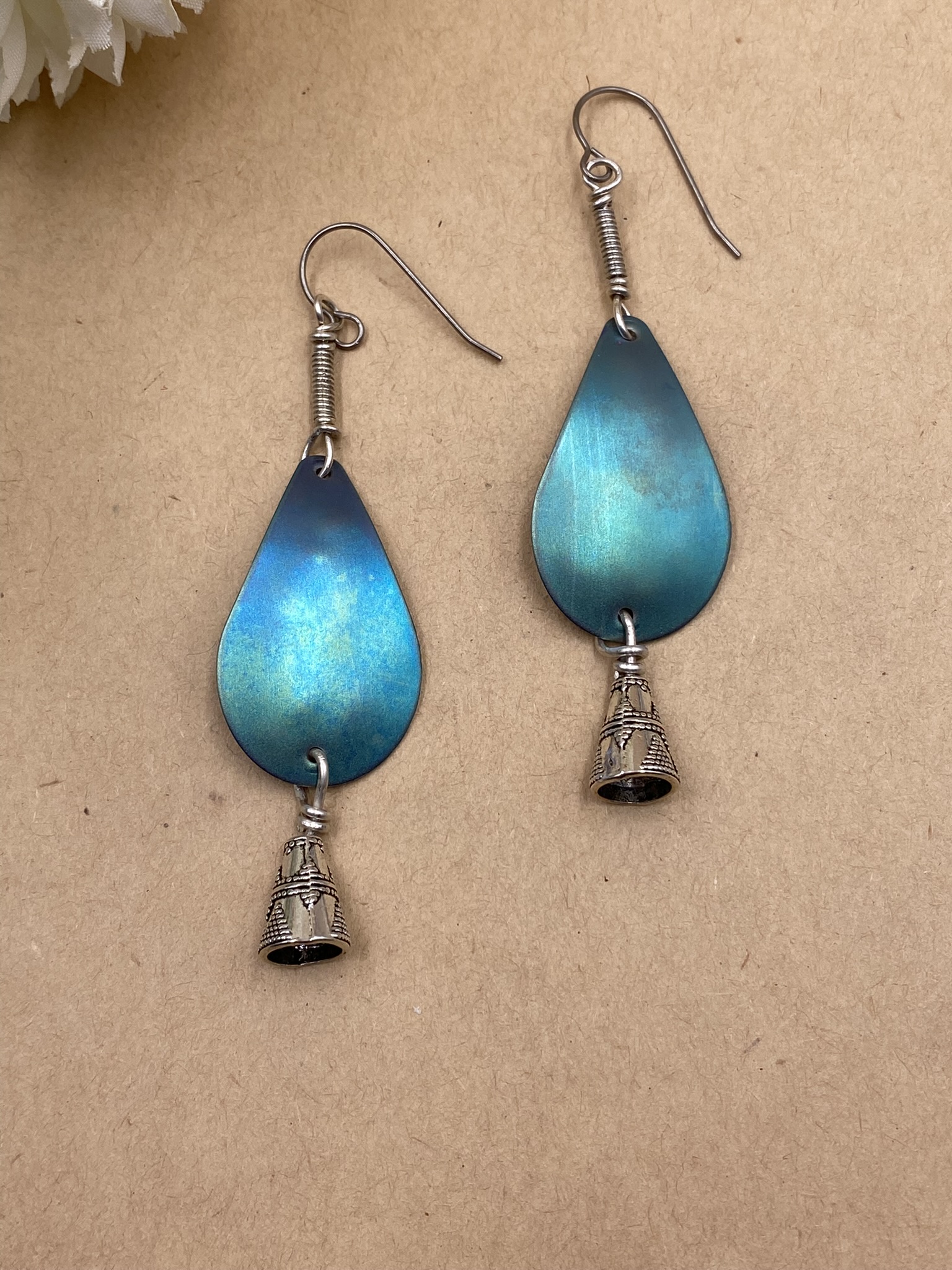 Teal green titanium teardrop shapes with silvery metal cone dangling below. Sterling silver coil above. Titanium ear wires. Lots of movement to these.