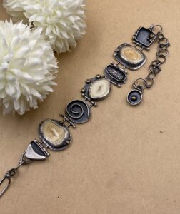 Sterling silver bracelet made up of varied components. Several have fossil walrus teeth slices in them. These are creamy to dark beige in color.
